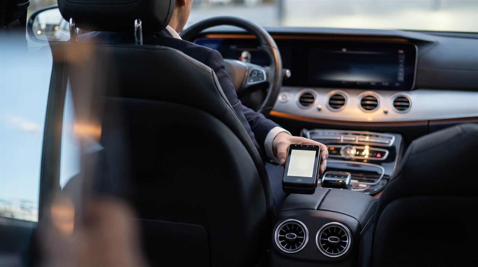 Chauffeur van Taxi Le Noir reikt het pinapparaat aan in de Mercedes